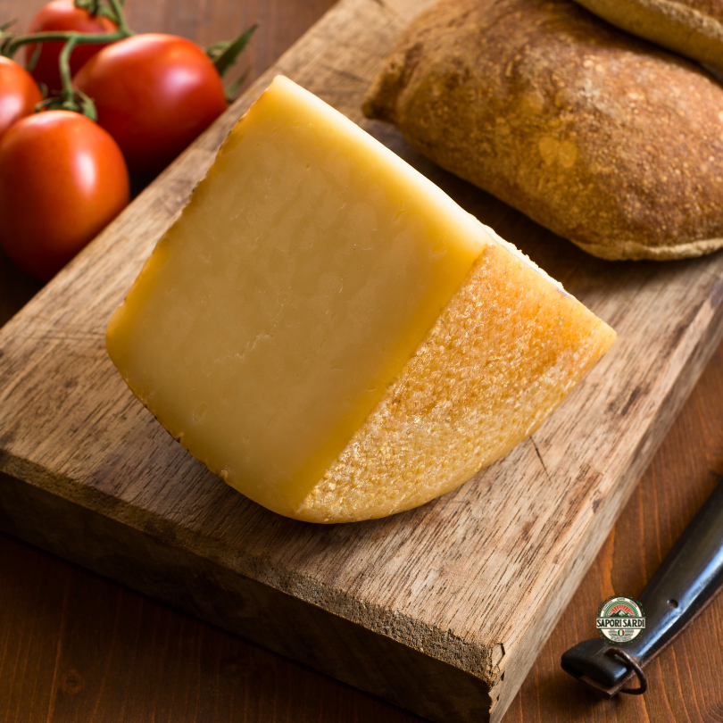 Pecorino Sardo Käse aufgeschnitten auf einem Holzbrett.